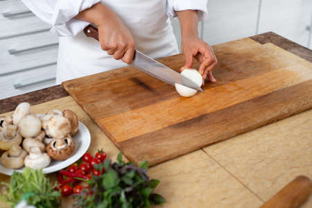 Close-up, cook starts cutting the onion into rings with a knife.の写真素材
