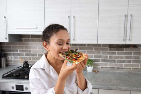 The young female chef tastes a vegan pizza without cheese.の写真素材