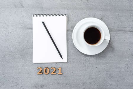 New year 2021. Flat lay of office space with the coffee cup, notepad, pencil and wooden numbers.の写真素材