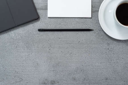 Flat lay of the office space with a view of a tablet with a gray case, a notebook with a pencil and a cup of coffee.の写真素材