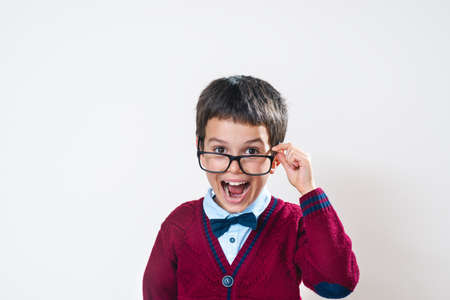 The schoolboy in a sweater looks at us holding glasses with his mouth open. Conceptual. Copy space.