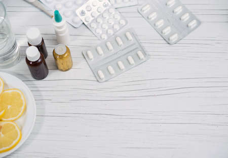 Still life of medicines for home treatment of the viral infection, a plate with sliced lemon. Pandemic, on self-isolation.の写真素材