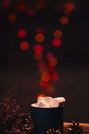 Still life. Vertical frame. The cup with marshmallows on a background of colored lights. Illusion of lights flying out of the cup.の写真素材