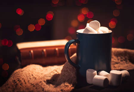 Still life. The cup with marshmallows on a background of colored lights. In the background, a book bound in leather.の写真素材