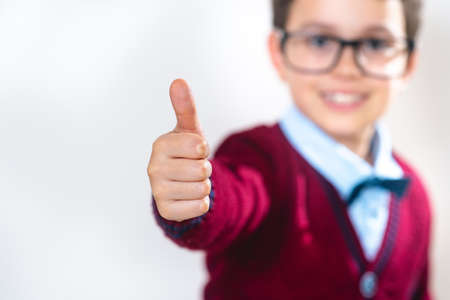 The schoolboy in a sweater shows a thumb up to the camera. Conceptual. Copy space.の写真素材
