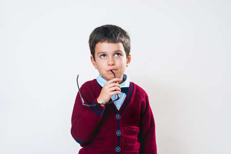 The schoolboy in a sweater stands with a pensive expression on his face. Conceptual. Copy space.の写真素材