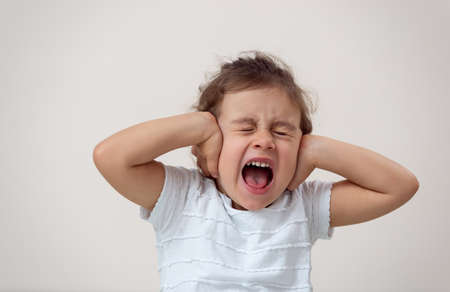 A little girl with a bright background screams the closing of her eyes and ears.