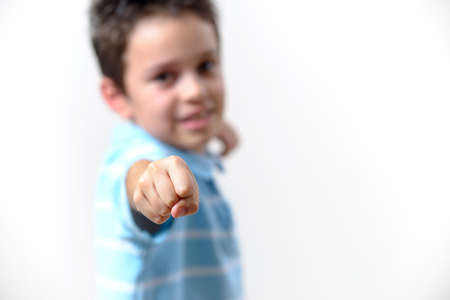The boy in a blue T-shirt shows his fist to the camera. Focus on the fist.の写真素材