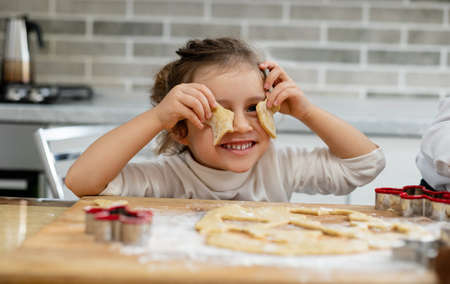 A girl puts the blanks of their dough to their eyes.