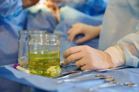 Surgery. Operating room nurse's hand rests on the instrument table.