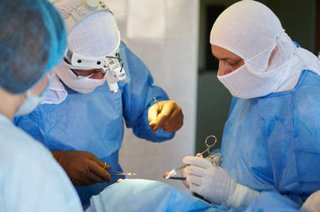 Surgery. Team of surgeons in blue suits stitch up the wound.
