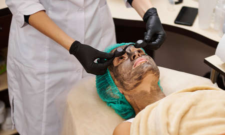 Beautician puts black safety glasses on the patient before the procedureの写真素材