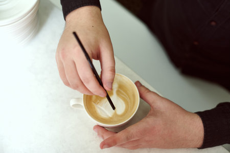 Close_up of barista's hands while making a latte. Focus on hands while making a latte artの写真素材