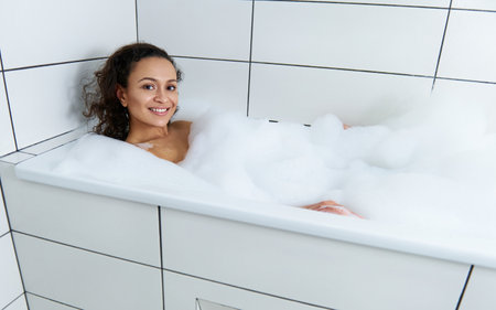 Happy beautiful woman relaxing in a bubble bath tubの写真素材