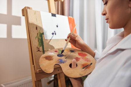Focus on paintbrush. Brunette woman painting at home.の写真素材