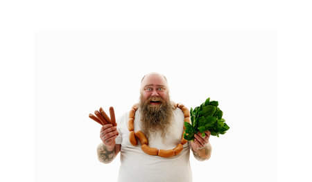 An obese man with sausages around the neck holding sausages and spinach on hands.