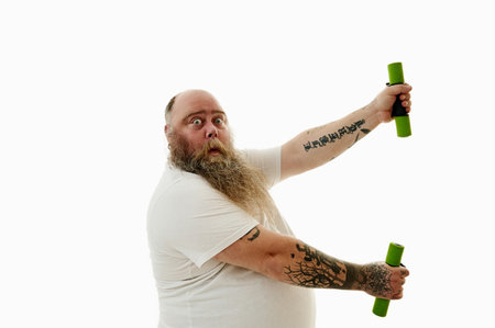 Portrait from the side of an obese man exercising with dumbbells expressing surprise.の写真素材