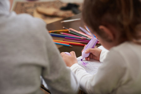 Angle view of two children drawing at home. Color pencils on the glass tableの写真素材