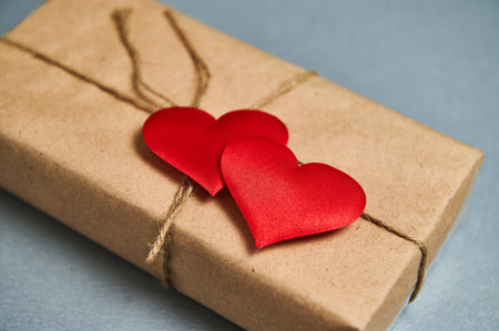 St. Valentines Day concept. A Saint Valentine Day's gift in eco paper and red hearts on a gray...