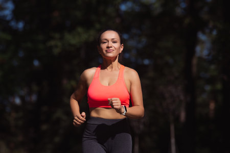 Smiling young woman runner in sportswear enjoying running outdoor.
