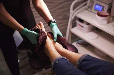 Closeup of beautician's hands and feet of woman having a pedicure in a beauty spa. Body care conceptの写真素材