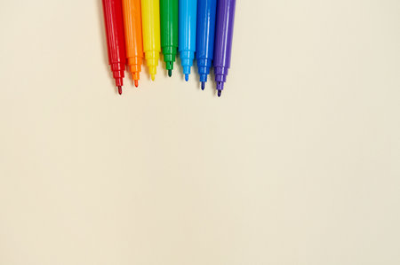 Rainbow-colored markers on yellow drawing paperの写真素材