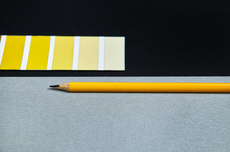 Designer colored swatches and wooden pencil on black background. Gradient of yellow on the color...