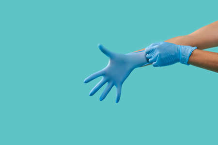 Side portrait of unrecognizable person hands wearing blue medical protective sterile latex gloves...