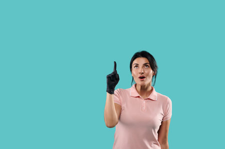 Surprised young woman looks up pointing her index finger at the top