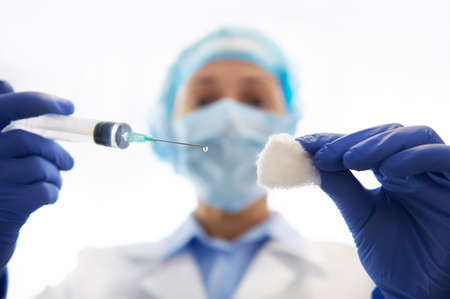 Close-up shot of syringe with biological injection in hands of doctor immunologist vaccinating at...