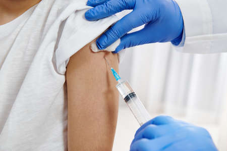 Pediatrist makes vaccination to child hand. Closeup.