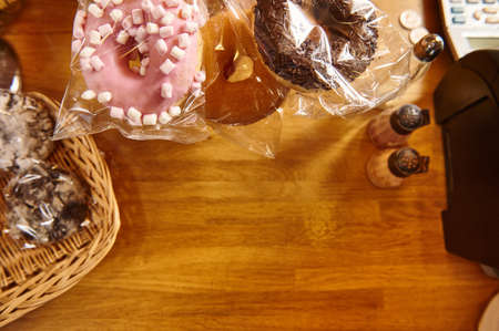 Doughnuts with various glaze and bakery products on a wooden surface. Flat lay composition with copy...