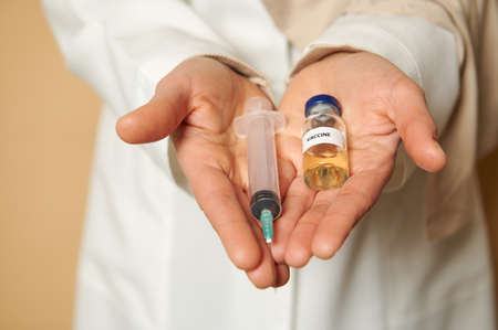 Close-up of female doctor hands holding a syringe and vaccine against an infectious disease. The...