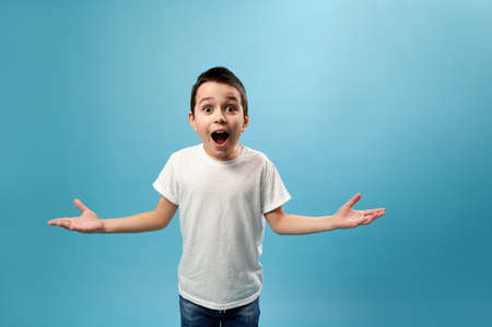 Shocked boy expressing surprise on camera. Facial emotions on blue background with copy spaceの写真素材