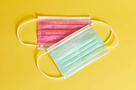 Flat lay of multicolored medical protective masks on yellow background with copy space.