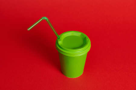 Studio shot of green takeaway paper mug with straw on red background. Copy space. Shot with soft...