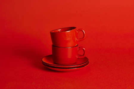 Two red porcelain cups and saucers on red background with soft shadow, copy space.の写真素材