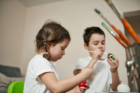 Side view of two adorable children coloring eggs for Easter.の写真素材
