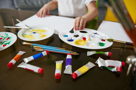 Multi-colored tubes with paints and a palette lying on a glass table. Closeup of art toolsの写真素材