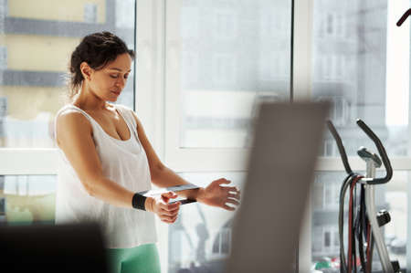 Side portrait of a young woman exercising with rubber elastic band at home. Workout, stretching, fitness at homeの写真素材