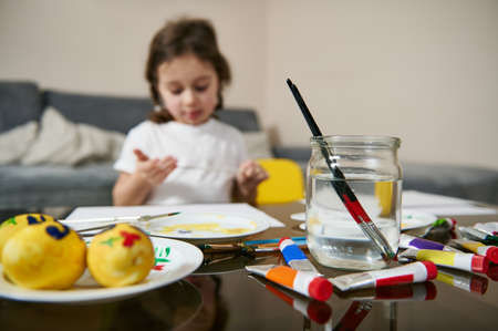 Cute little girl with braids sitting at table and drawing or painting . Children's creativity concept. Art educationの写真素材