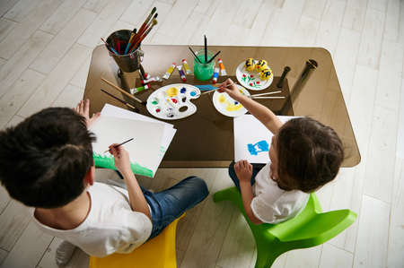 Two adorable children drawing and creating with watercolor paints at home.の写真素材
