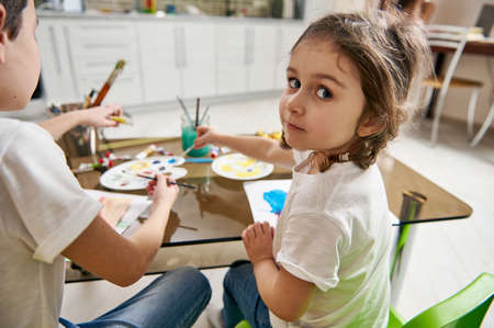 Beautiful girl looking with braids over her shoulder at the camera while art learning creativity at homeの写真素材