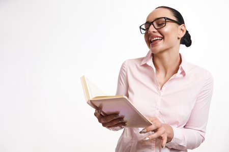 Young business woman laughing while looking at a diary in her hands. White background with copy...