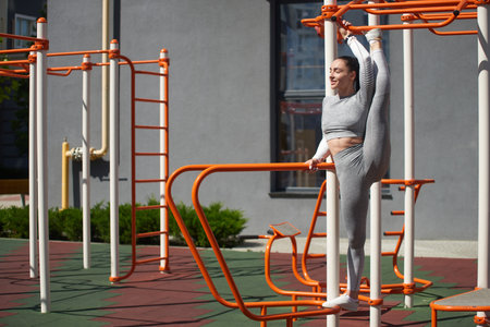 The young woman in a tracksuit stands with her leg raised above her head. Sports, stretching.
