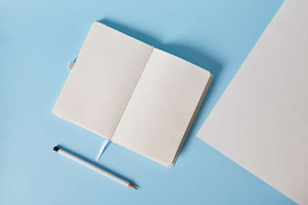 Flat lay composition of white writing tools on blue background. Space for text