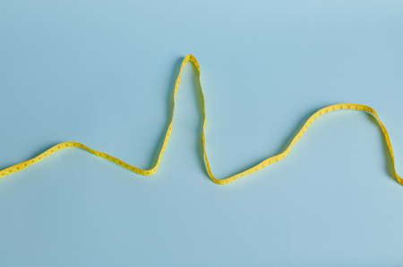 Flat lay of the measuring tape laid out in the form of PQRST segments on the cardiogram. Isolated on blue background with copy spaceの写真素材