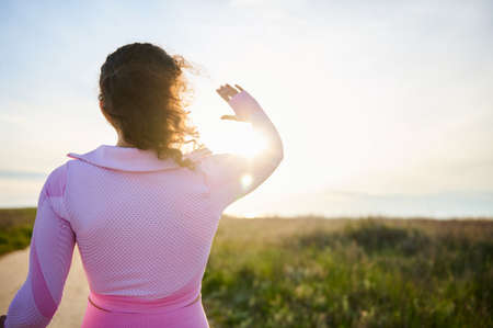 Rear view of a sportive brunette woman standing with her back to the camera against the background...