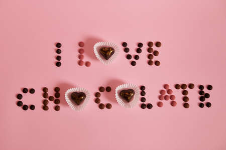 Top view of I LOVE CHOCOLATE lettering laid out from multi colored chocolate pills and pralines on...
