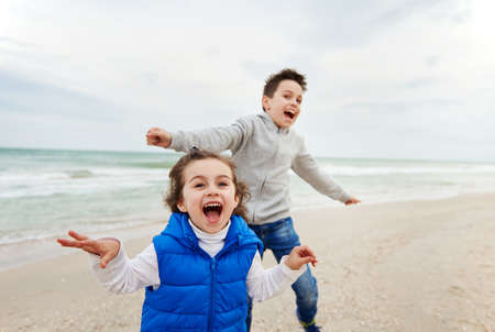 Two adorable children, boy and girl, laughing and playing on the beach. Happy childhood concept. International Children's Dayの写真素材